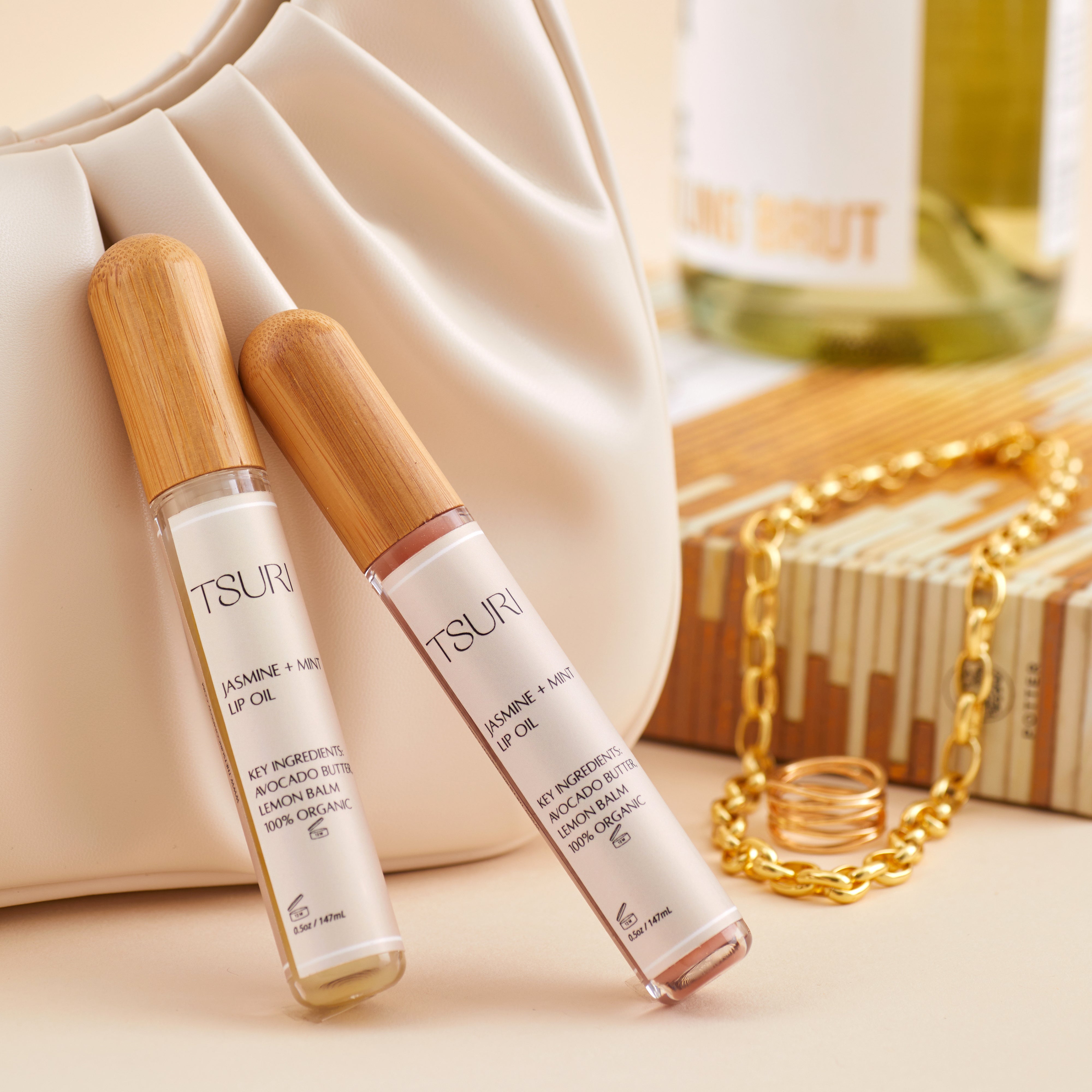 Jasmine + Mint Lip Oil on a table with a handbag, featuring bamboo caps, designed for hydration and healing.