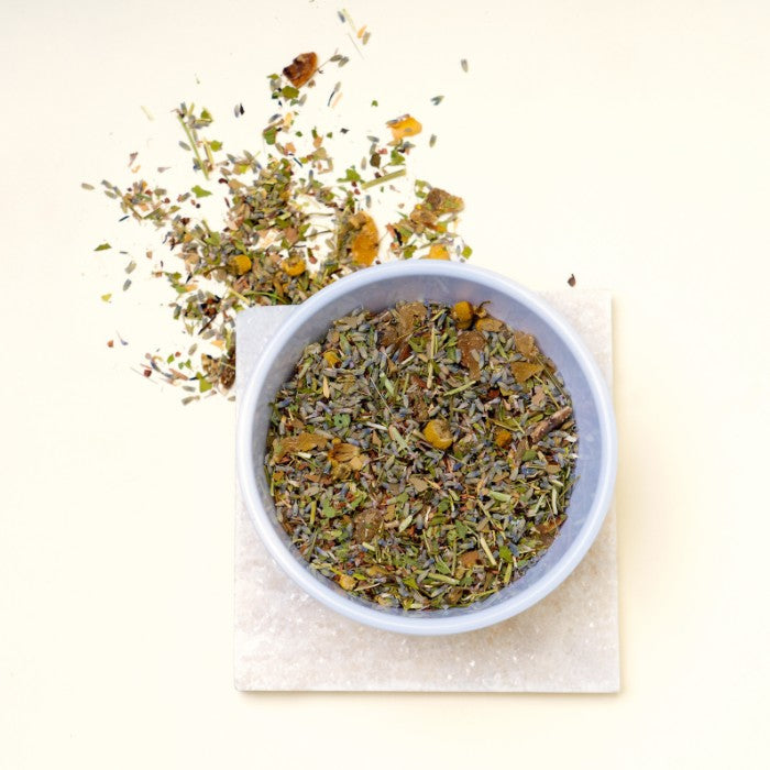 Bowl of Root loose leaf tea blend with lavender, chamomile, and honeybush for stress relief and self-care.
