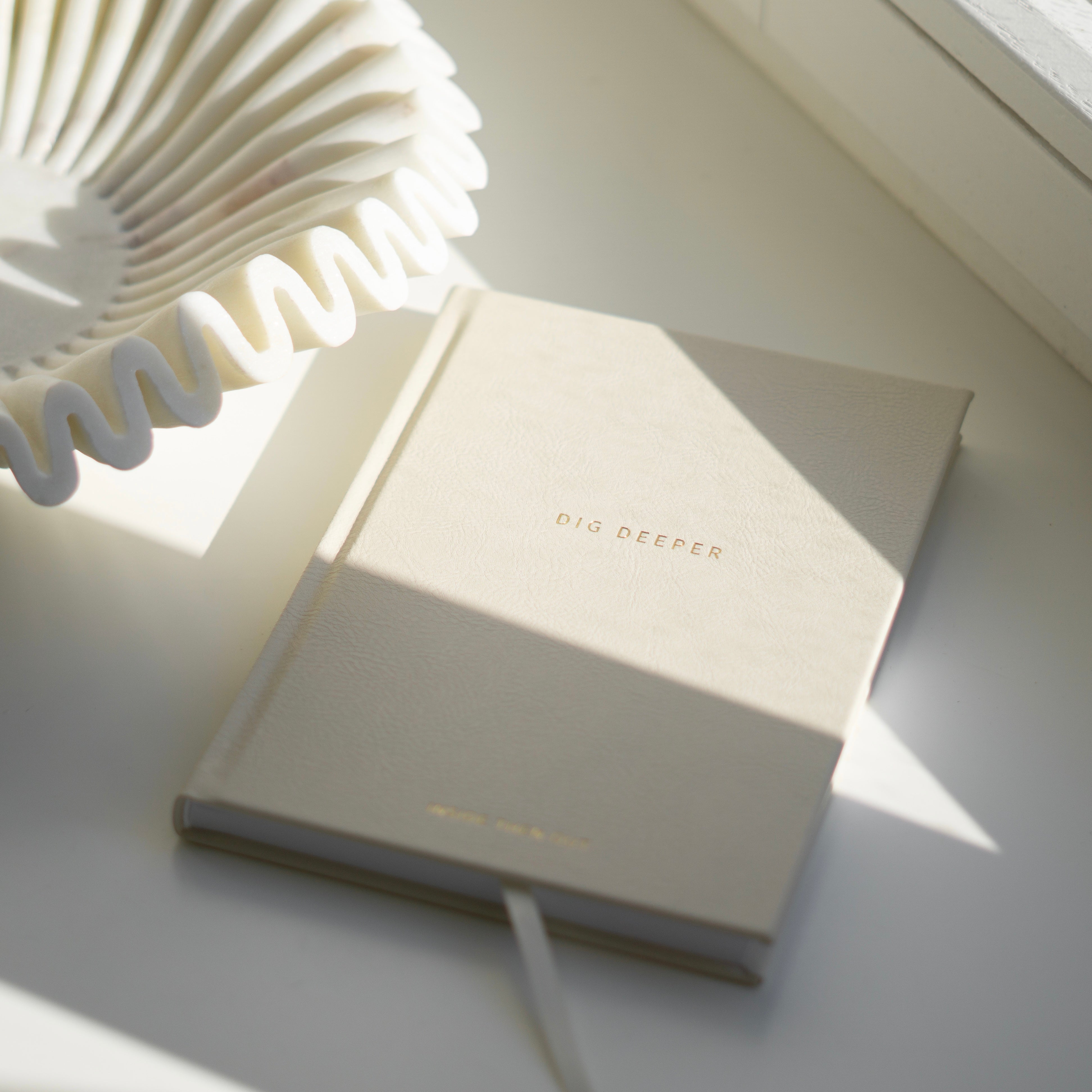 Dig Deeper Journal in soft lighting on a table, designed for personal growth and healing with 180 reflective prompts.