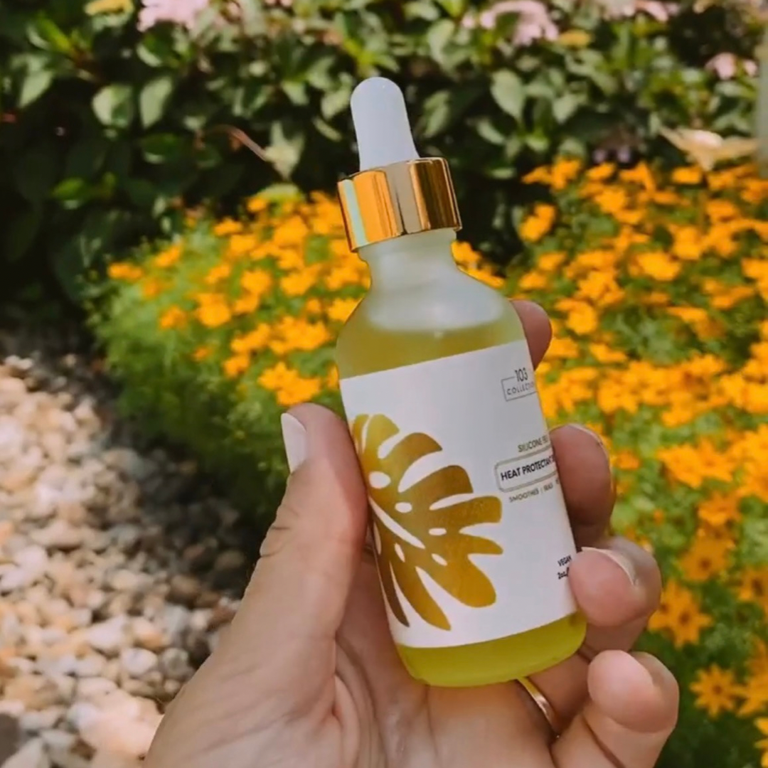 Person holding a bottle of Vegan Heat Protectant Serum in a garden setting, showcasing its natural and eco-friendly appeal.