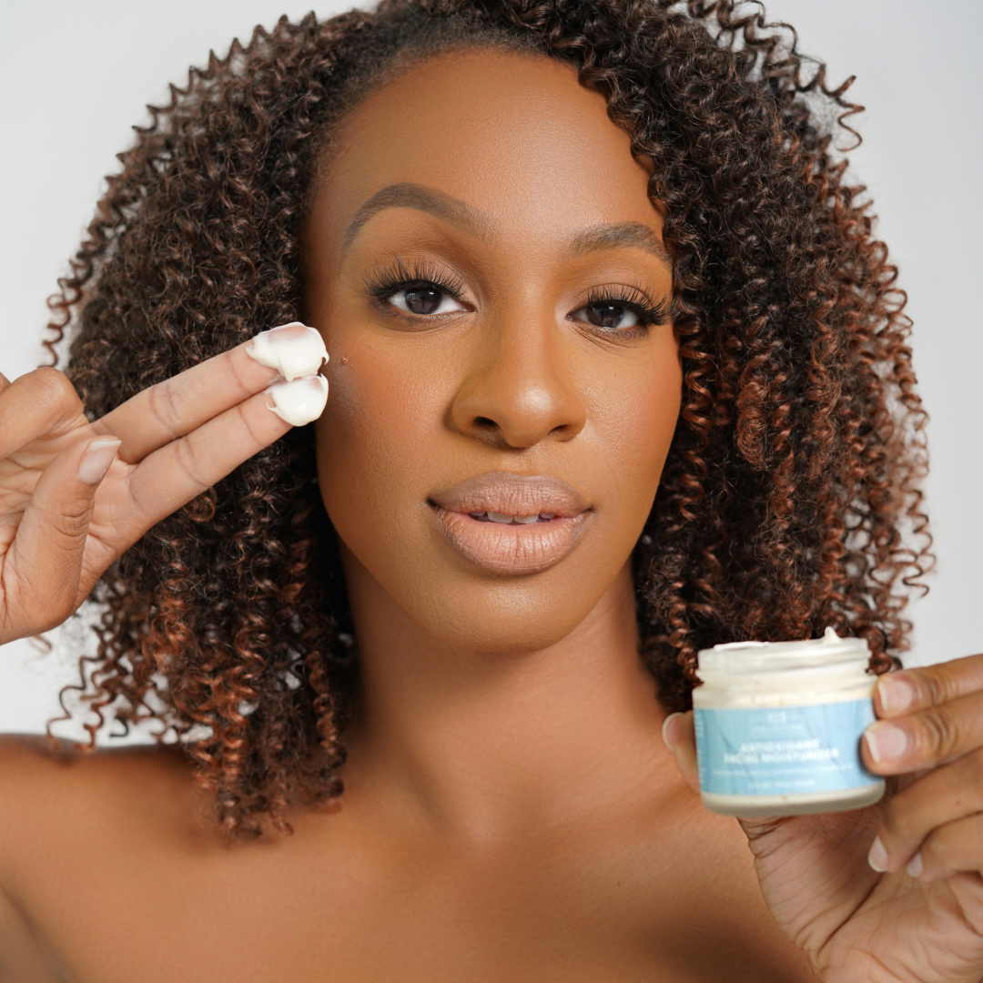 Woman applying vegan skin cream from Antioxidant Skin Care Bundle Deluxe for hydration and anti-aging effects.