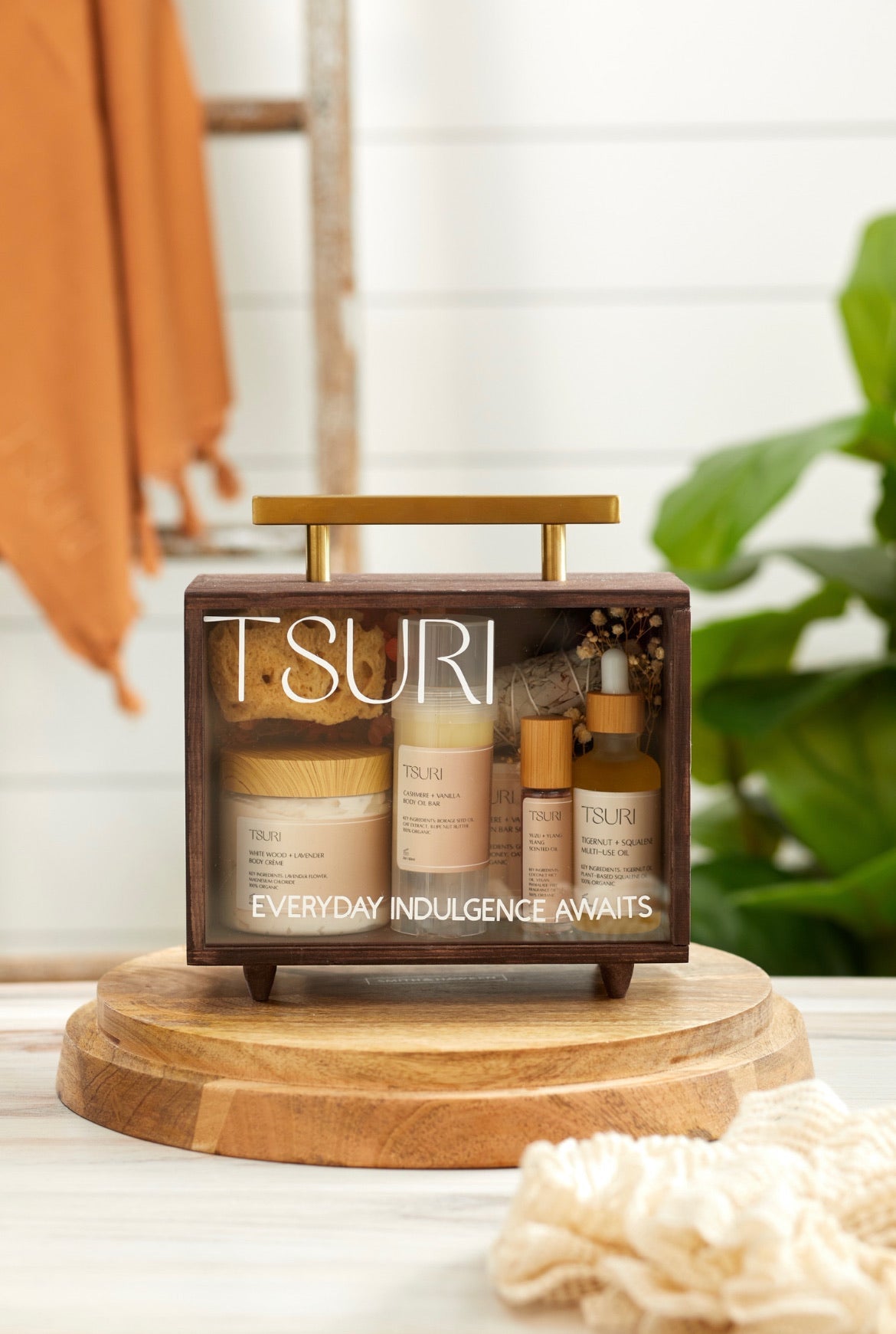 Tsuri Company Best Sellers Ritual Kit displaying luxurious body creams, oils, and soaps on a wooden stand, perfect for self-care.
