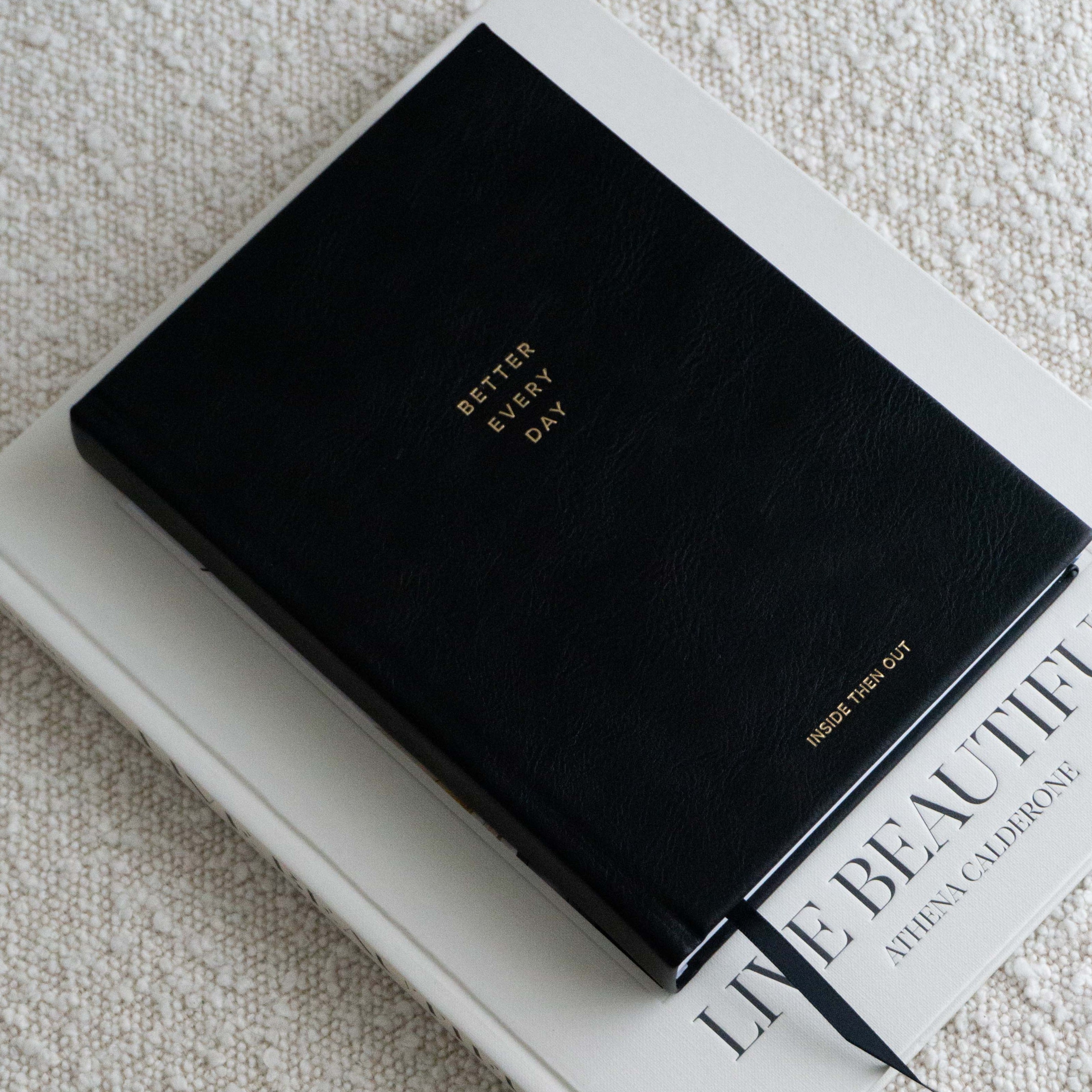Black Better Every Day Journal on a textured beige surface, featuring a guided self-care focus with 365 daily reflection prompts.