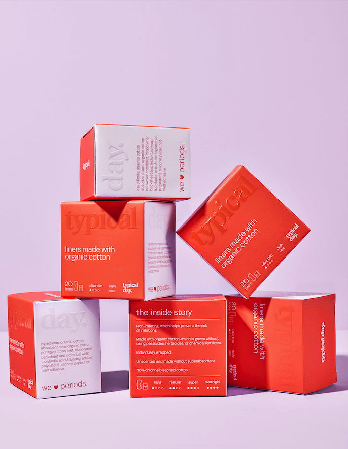 stack of bright orange panty liner boxes highlighting non-toxic, ultra-thin, and eco-conscious feminine care