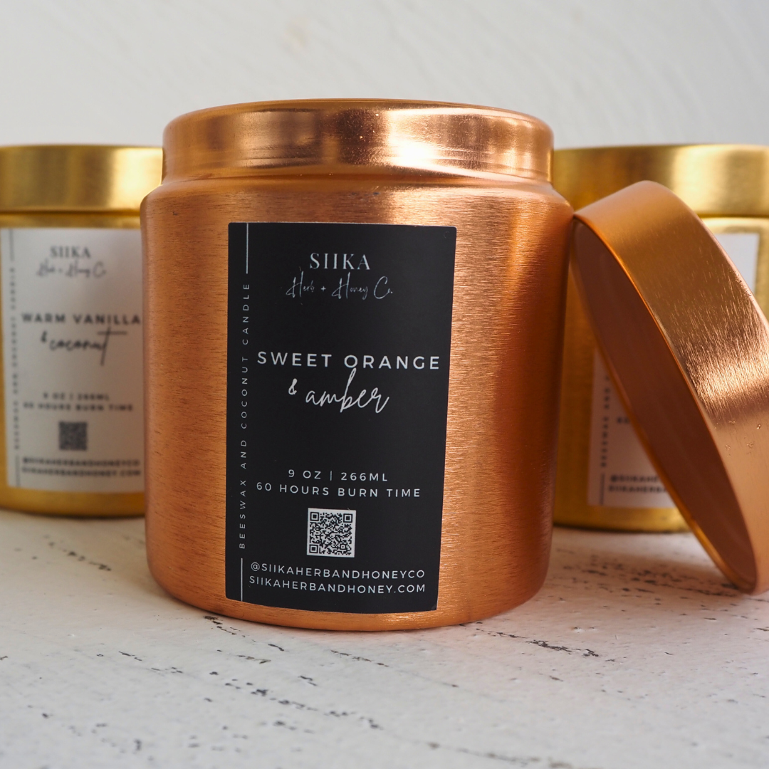 SIIKA Sweet Orange & Amber beeswax candle in a copper tin with wood wick, promises a warm autumnal aroma with 60 hours burn time.